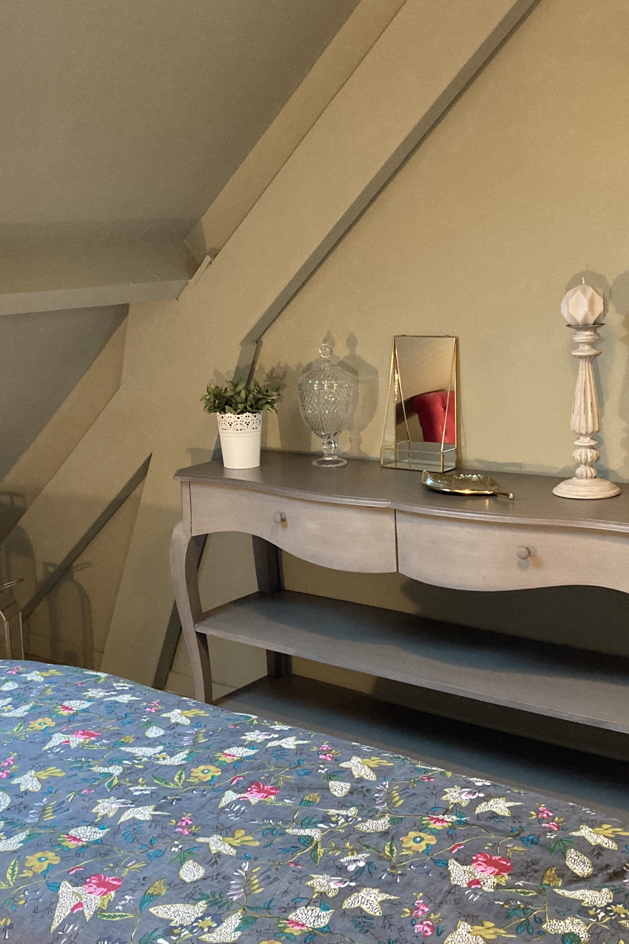 Lit avec couette à motif sur Blois, meuble en bois à Mesland, décoration avec style en rapport avec la chambre en Loir et Cher, plante en pot sur meuble en bois, jolie miroir avec décoration sur un meuble au bout du lit, 