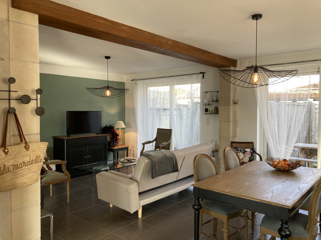 Salon avec canapé et table à manger à Blois, mur en pierre et poutre en bois dans un salon en Loir et Cher, fenêtre avec rideau blanc à Mesland, salon avec style ancien et moderne, table et chaise en bois,